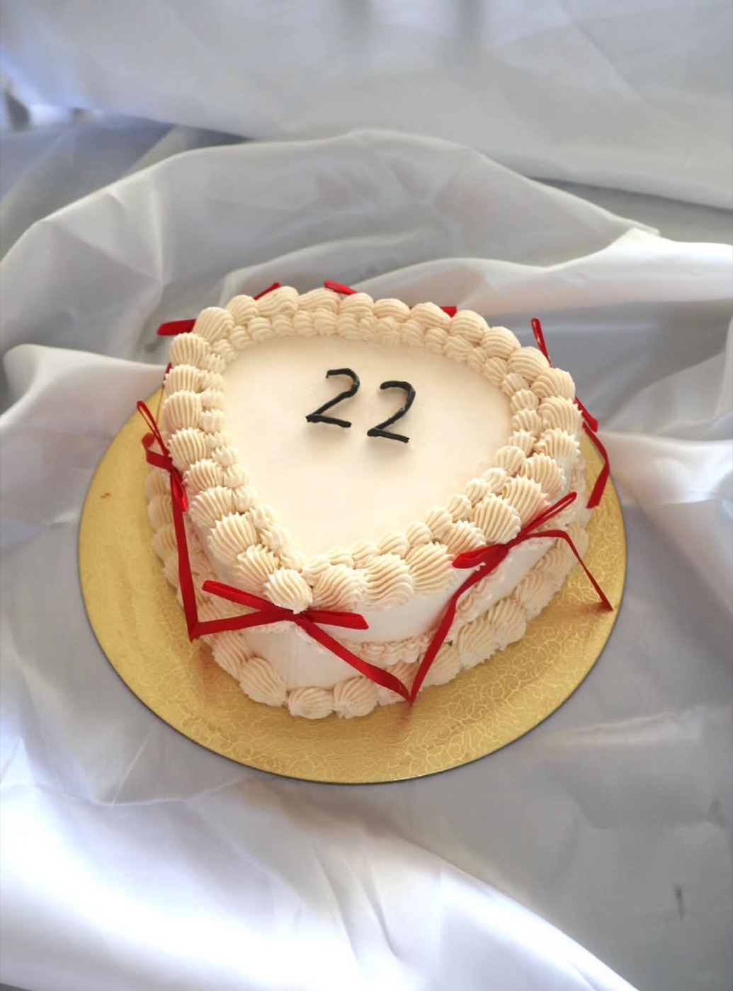 Weisse Herztorte mit roten Schleifen und der Zahl 22